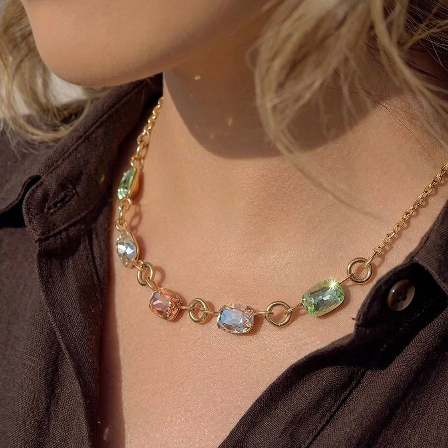 Multicolor cushion-cut crystal necklace on a model wearing a dark brown shirt.