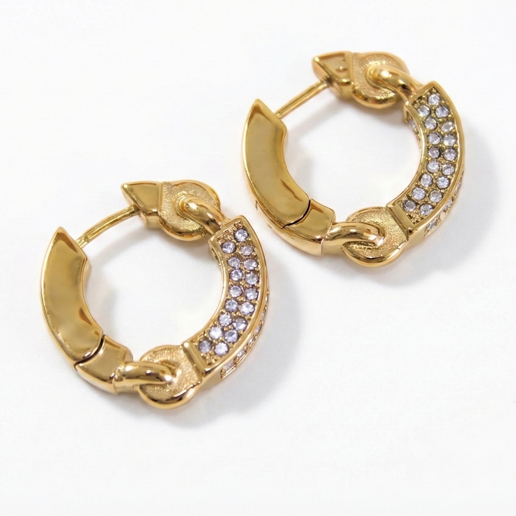 Macro close-up detail of cubic zirconia crystals embedded in gold stainless steel hoop earrings showing stone clarity and setting.
