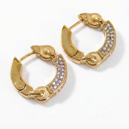 Macro close-up detail of cubic zirconia crystals embedded in gold stainless steel hoop earrings showing stone clarity and setting.