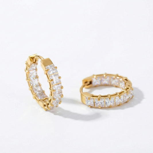 Pair of small gold huggie hoop earrings featuring a row of channel-set square-cut clear crystals, shown from a front and side angle on a white background.