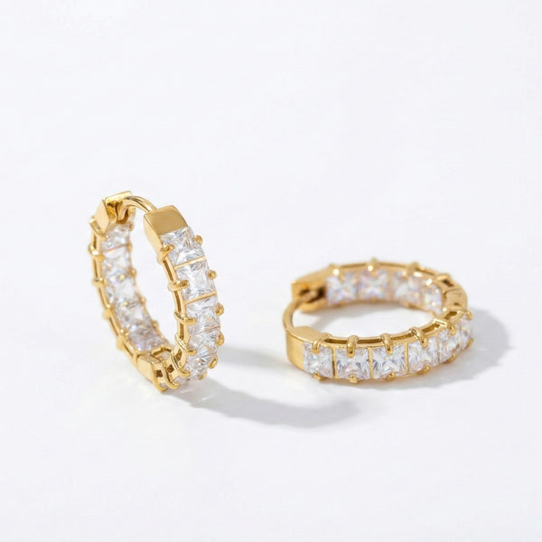 Pair of small gold huggie hoop earrings featuring a row of channel-set square-cut clear crystals, shown from a front and side angle on a white background.