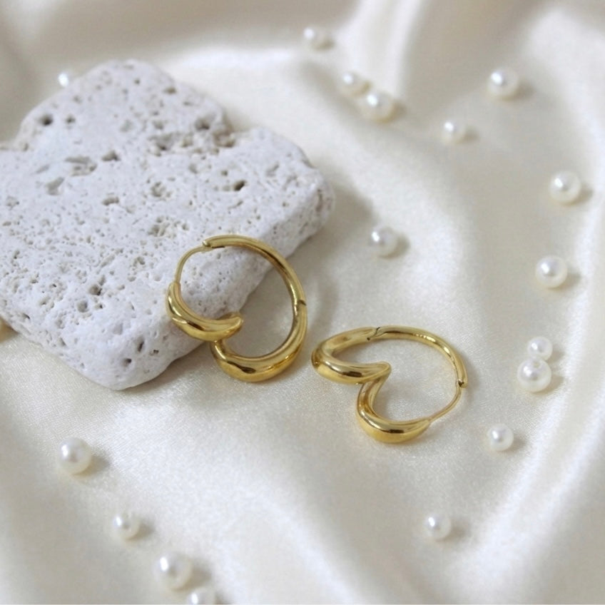 Gold twisted hoop earrings on white stone prop, anti-tarnish jewelry.