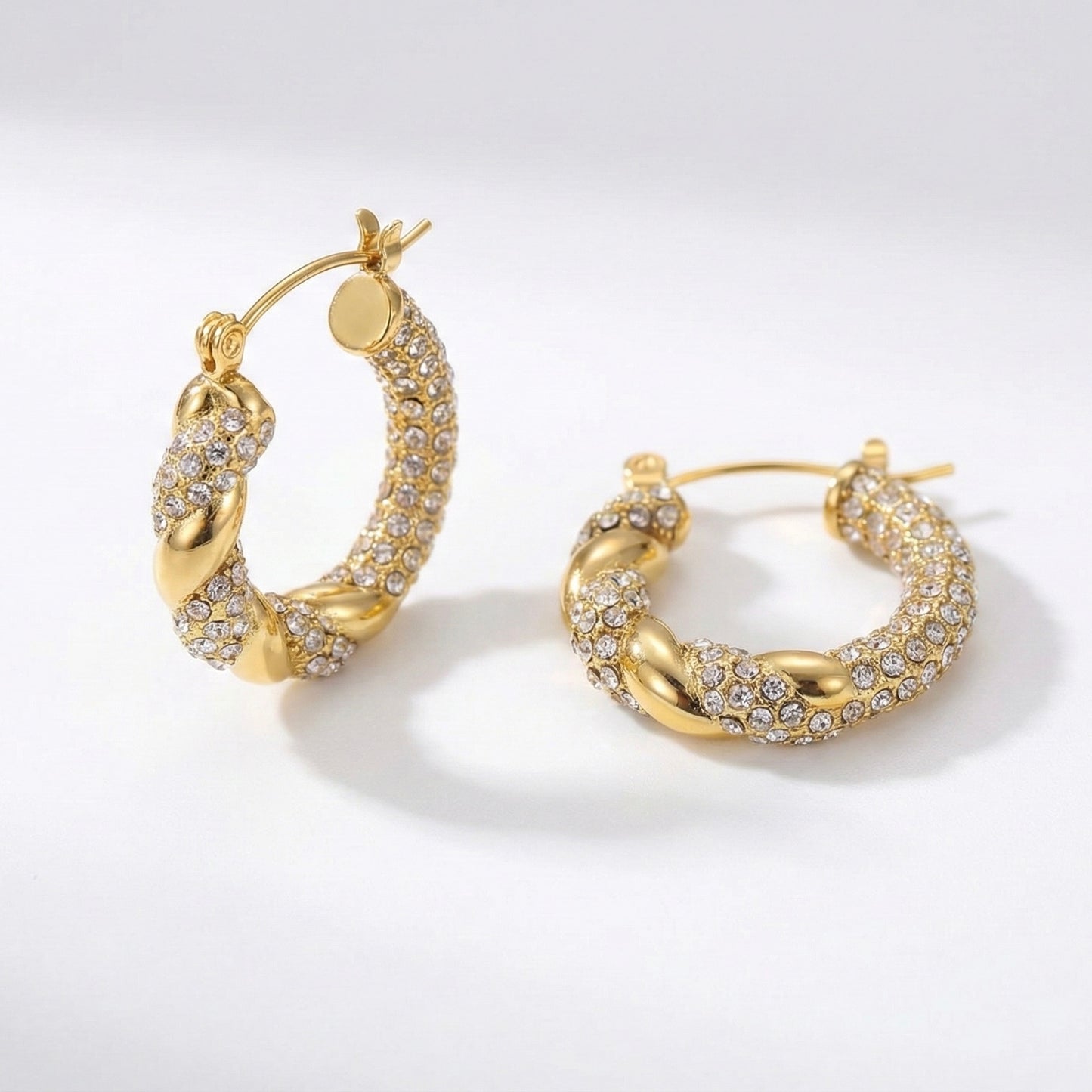 Gold hoop earrings with diamond accents on a light gray background
