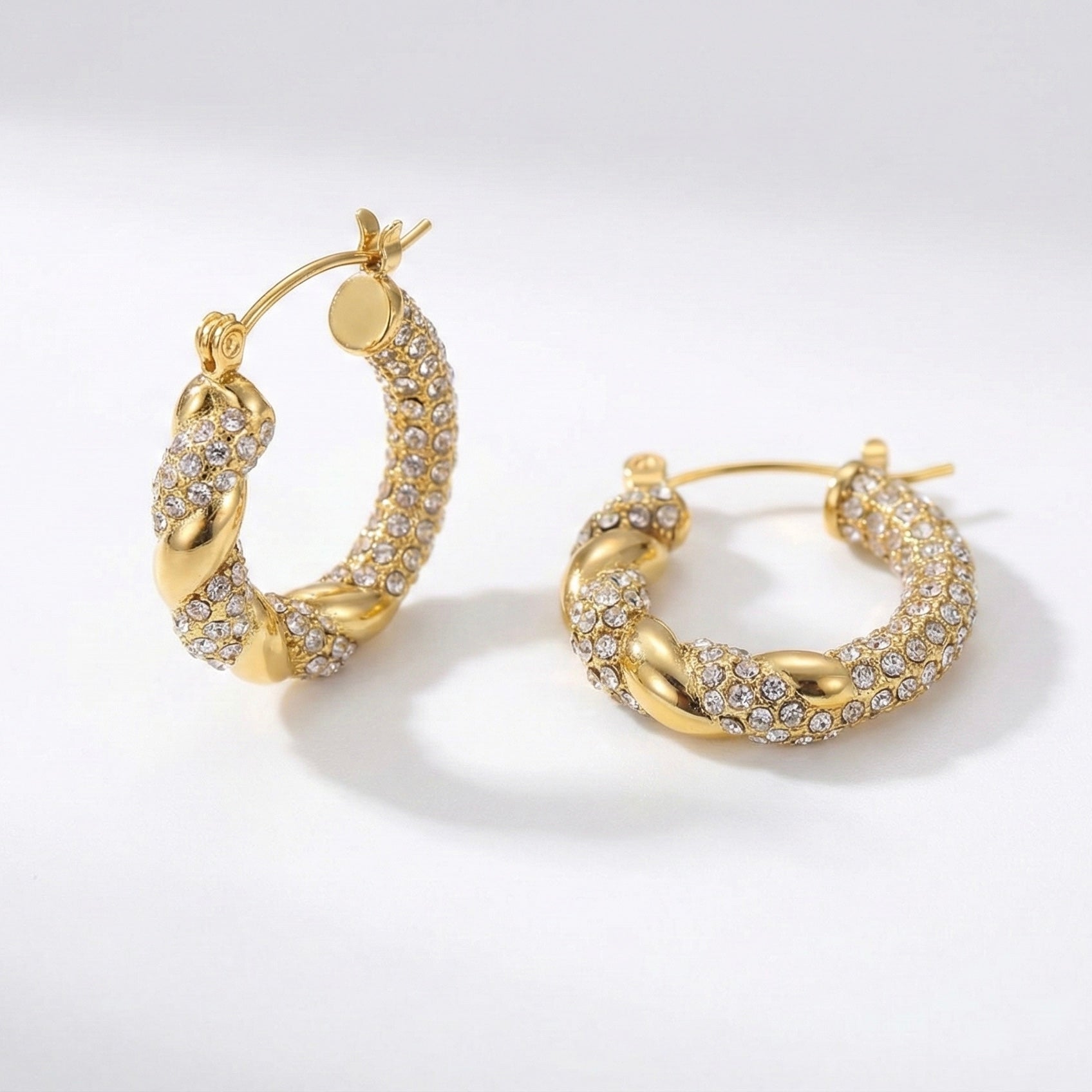 Gold hoop earrings with diamond accents on a light gray background