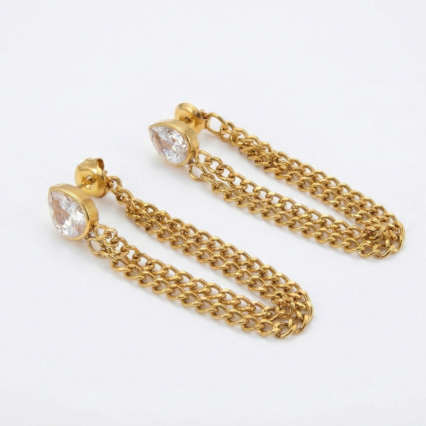 Gold chain earrings with clear gemstones on a white background