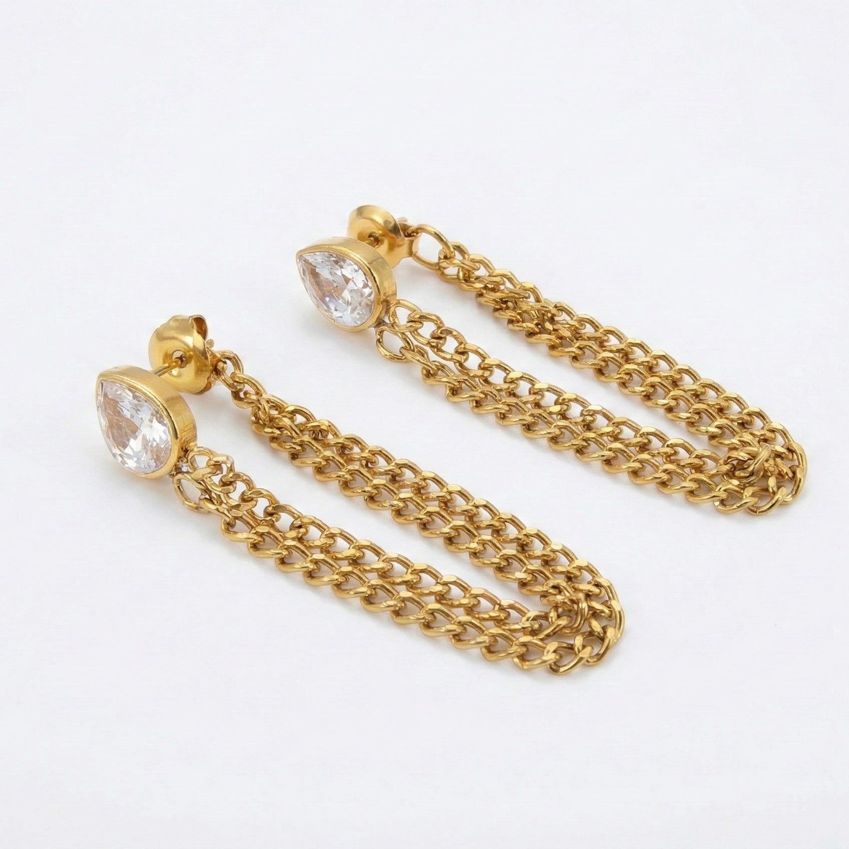 Gold chain earrings with clear gemstones on a white background