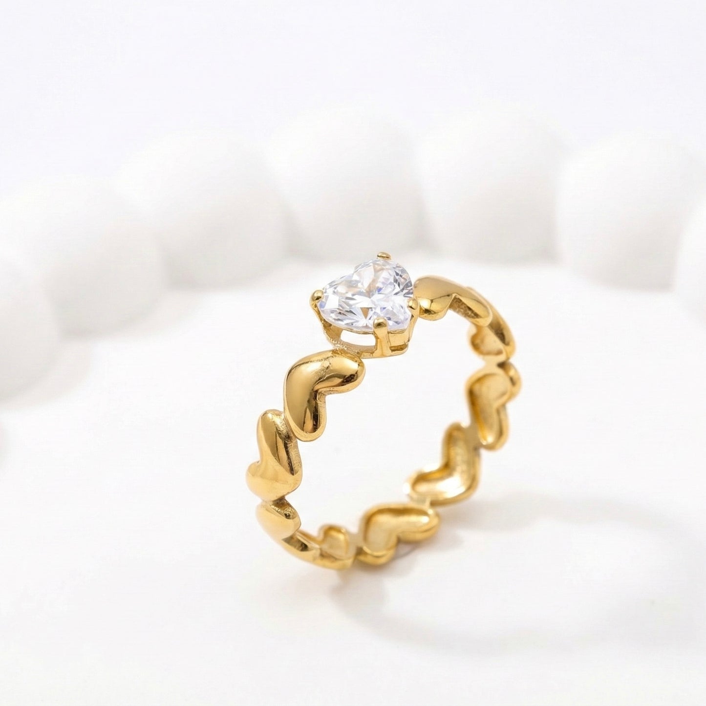 Gold anti-tarnish ring with heart-shaped crystal on a white aesthetic tray.