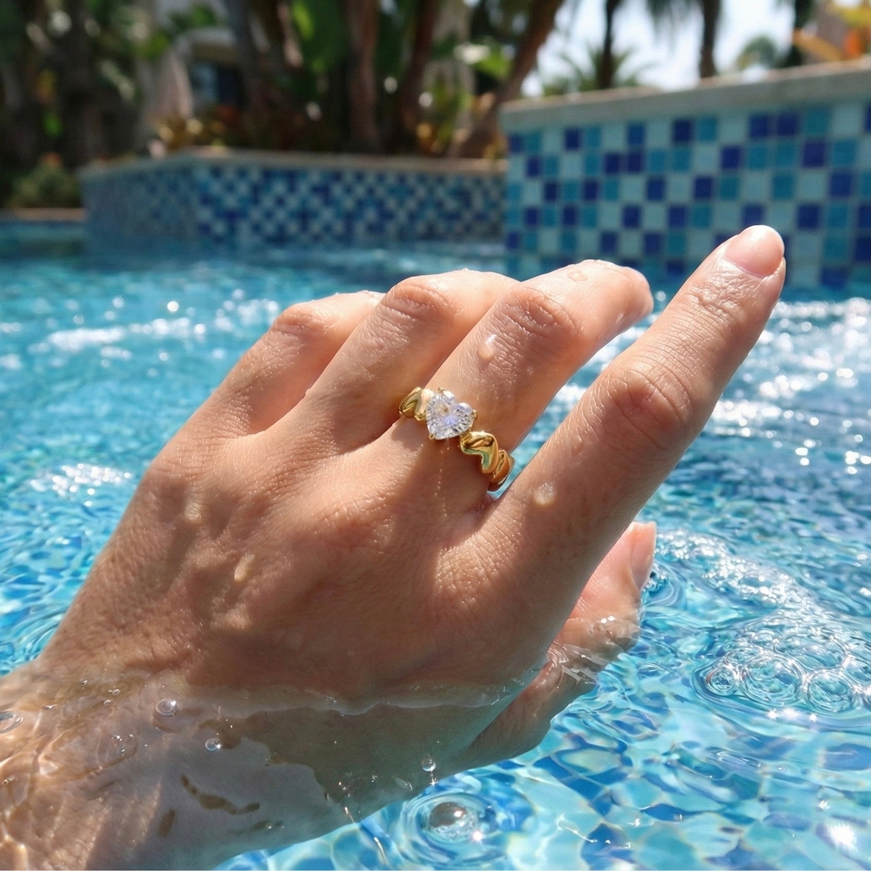 Hand with a gold and diamond ring in a pool
