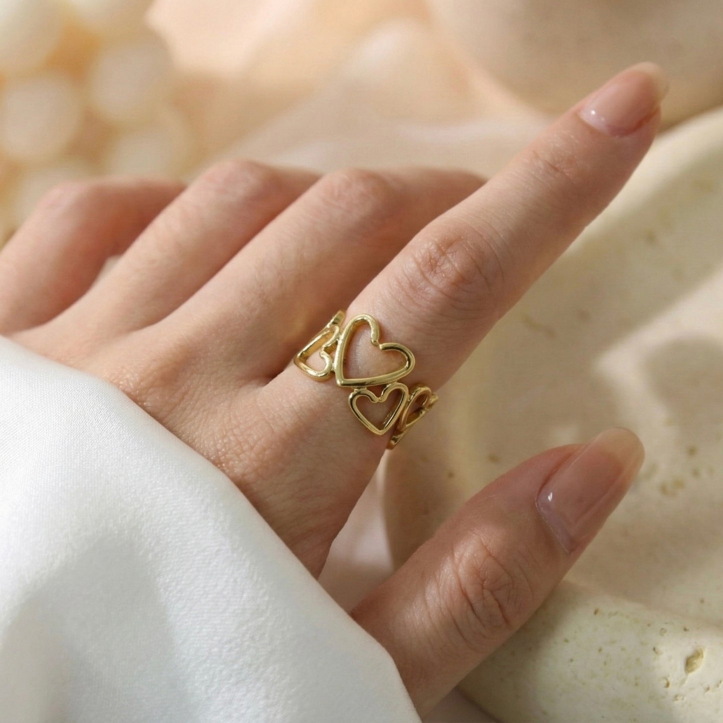 Gold heart-shaped ring on a finger with a soft background