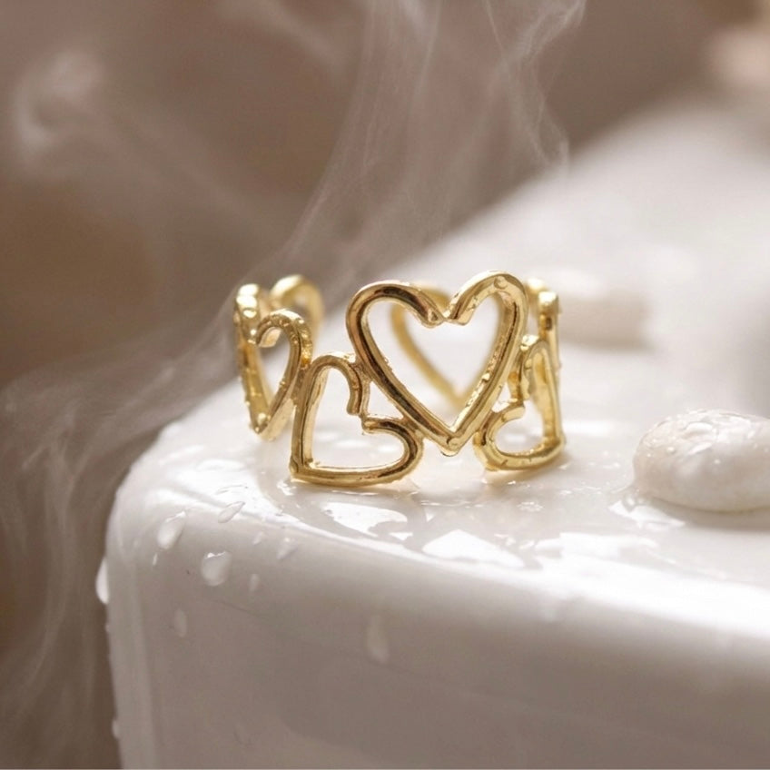 Gold heart-shaped ring on a white surface with a blurred background