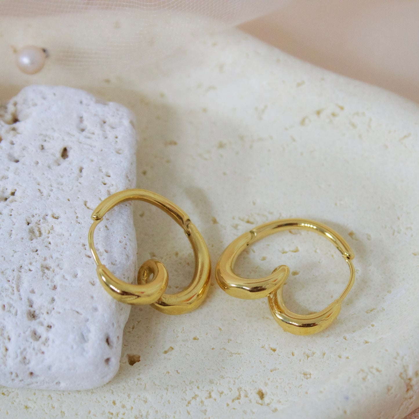 Gold hoop earrings on a textured white surface