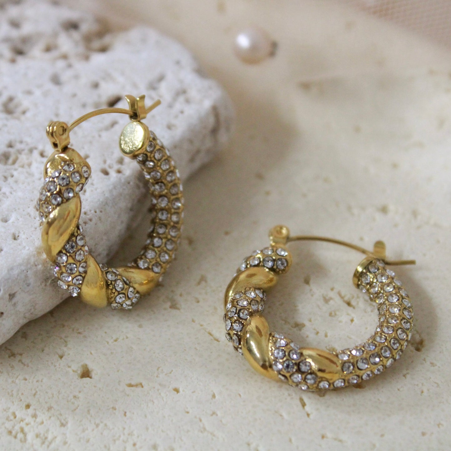 Side view showing the thickness and twisted texture of the gold Aurora pave hoops by Glow Petal.