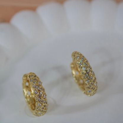 Gold huggie earrings with criss cross diamond pattern on white plate