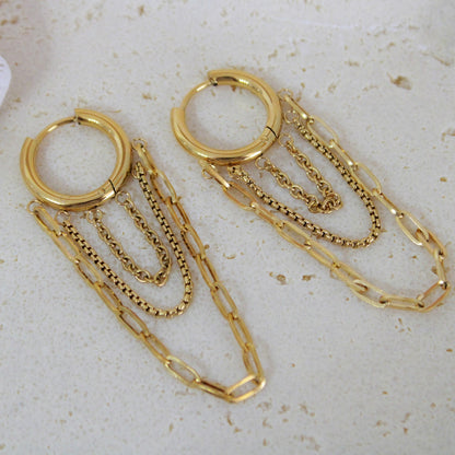 Gold hoop earrings with chain extensions on a light background