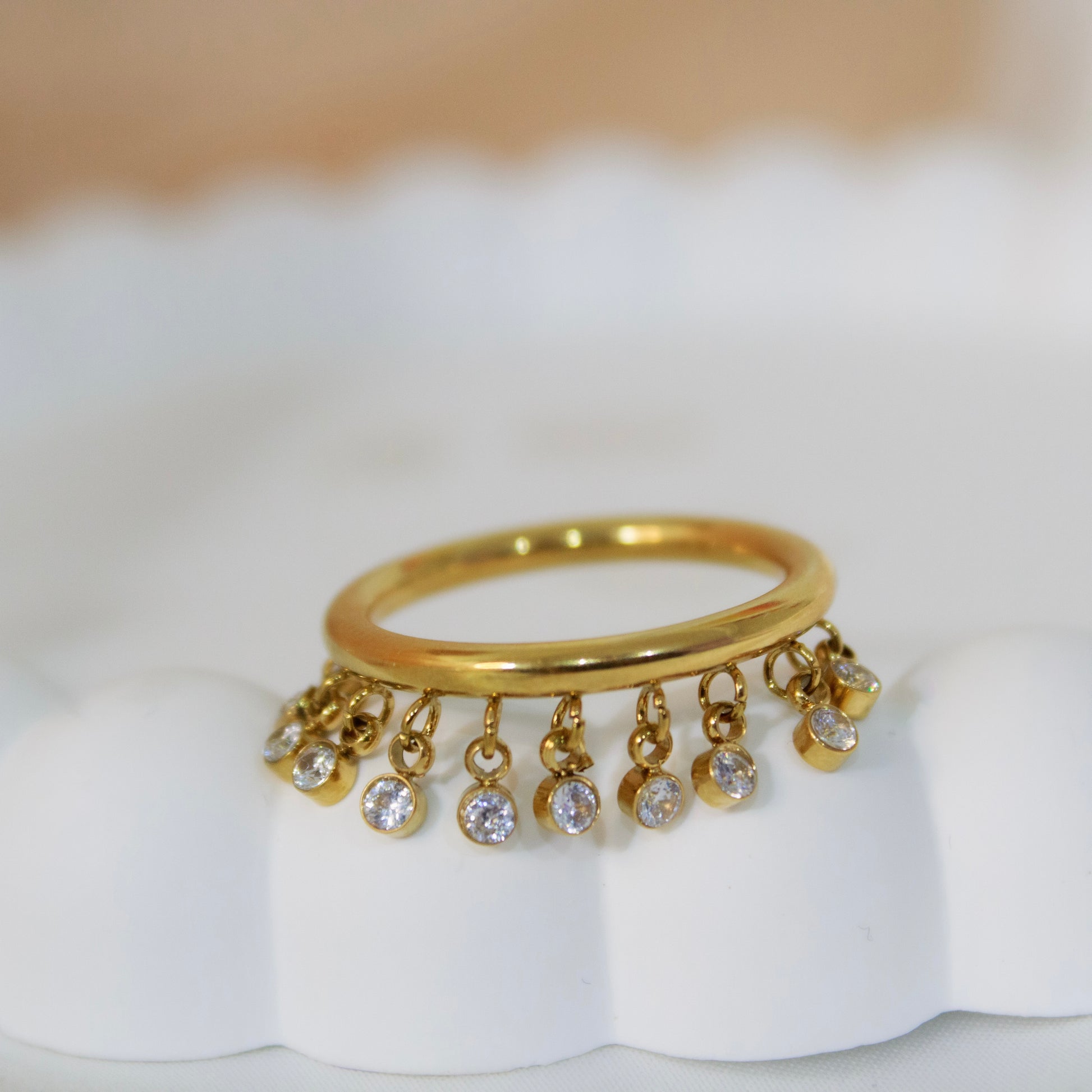 Waterproof gold shaker ring with moving cubic zirconia stones.