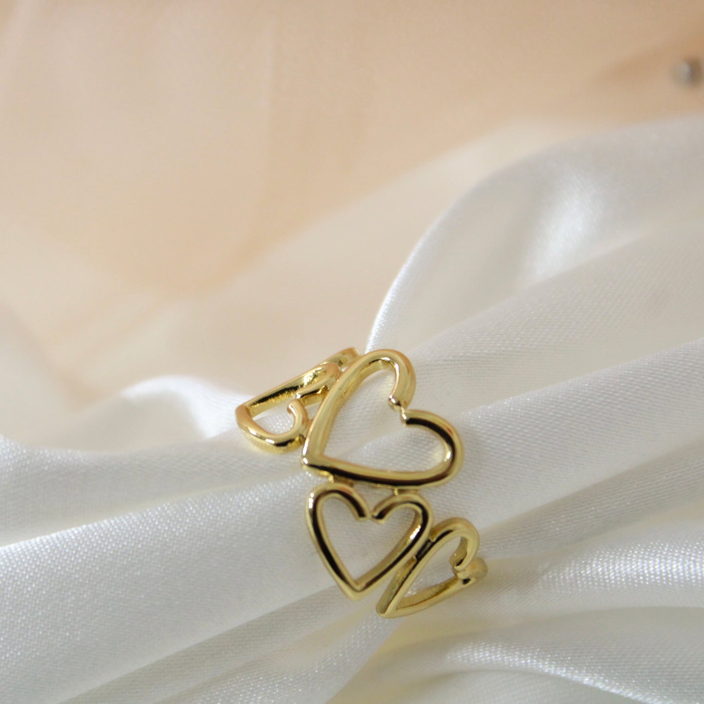 Gold heart-shaped ring on a white fabric background