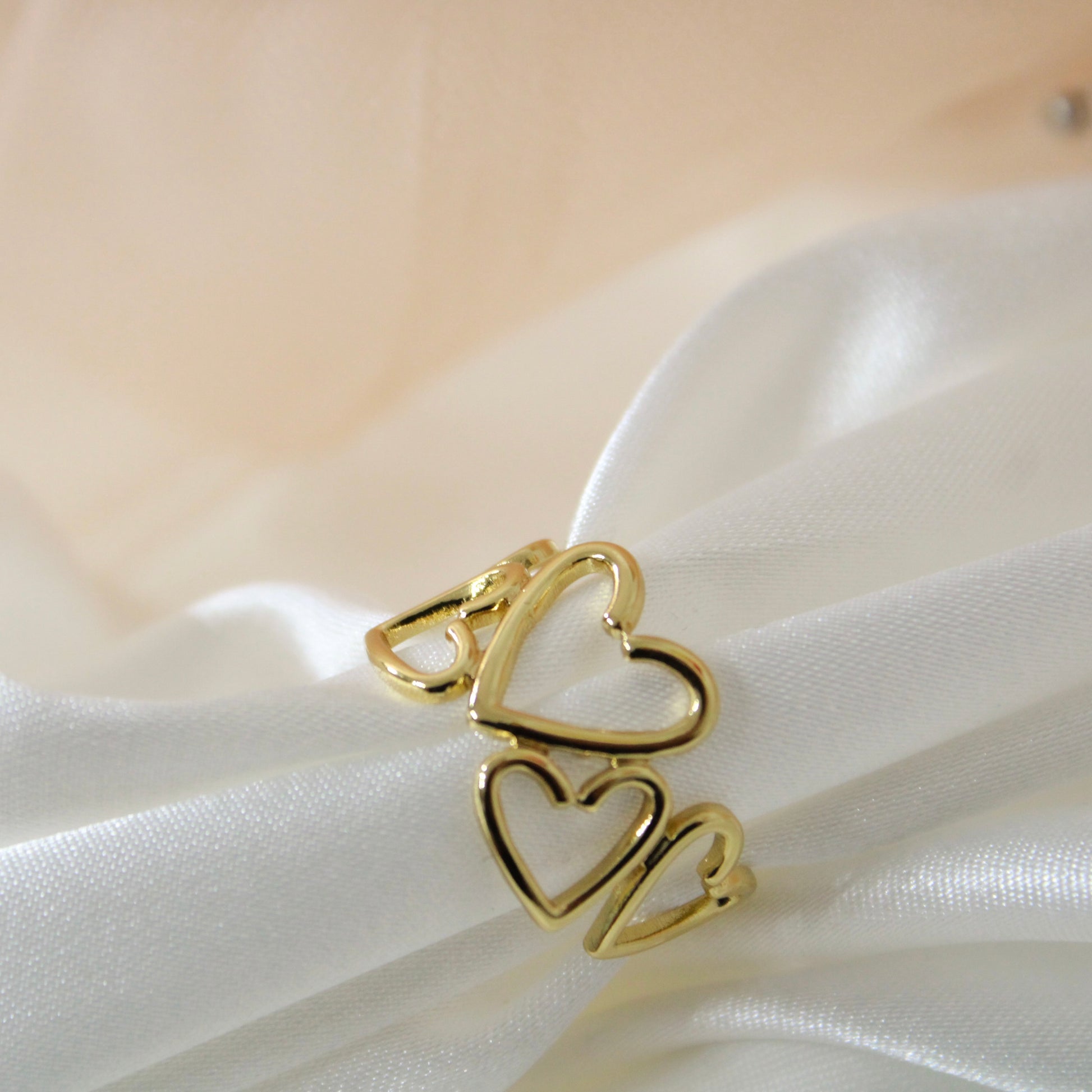 Gold heart-shaped ring on a white fabric background