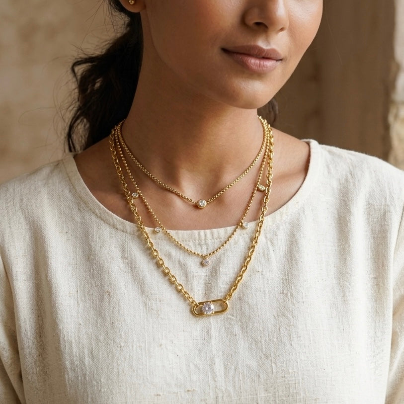Model wearing GlowPetalJewels triple layered gold pendant necklace with a white top.