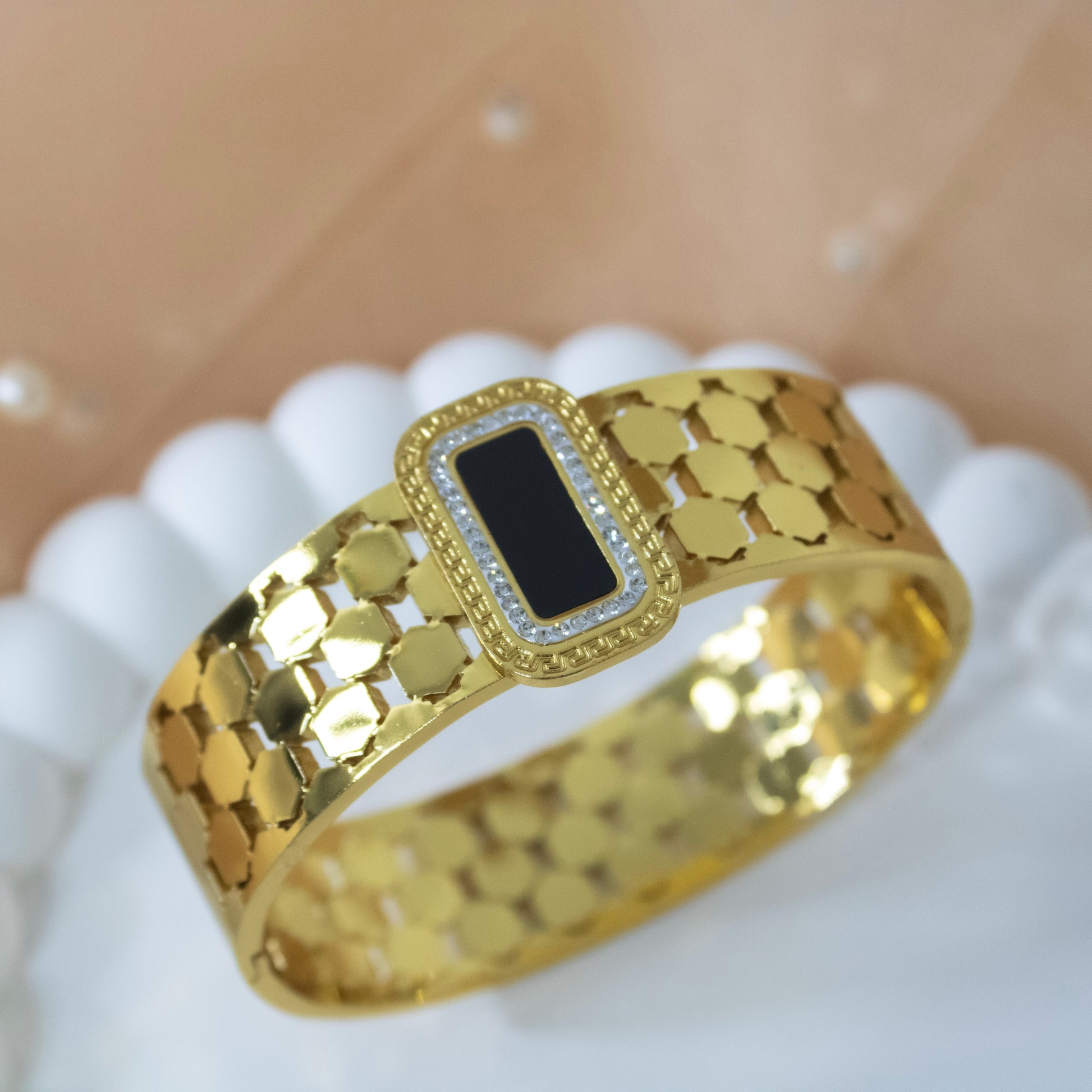 Gold bracelet with a black center on a white surface