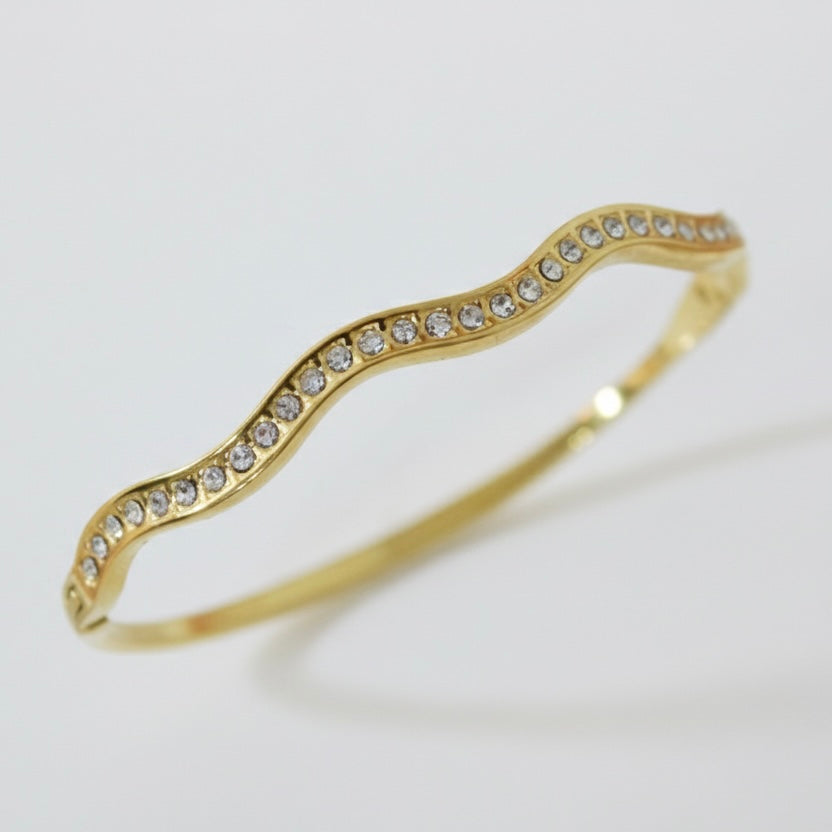 Gold bracelet with crystal stones on a light gray background