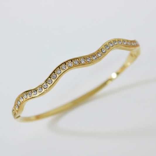 Gold bracelet with crystal stones on a light gray background