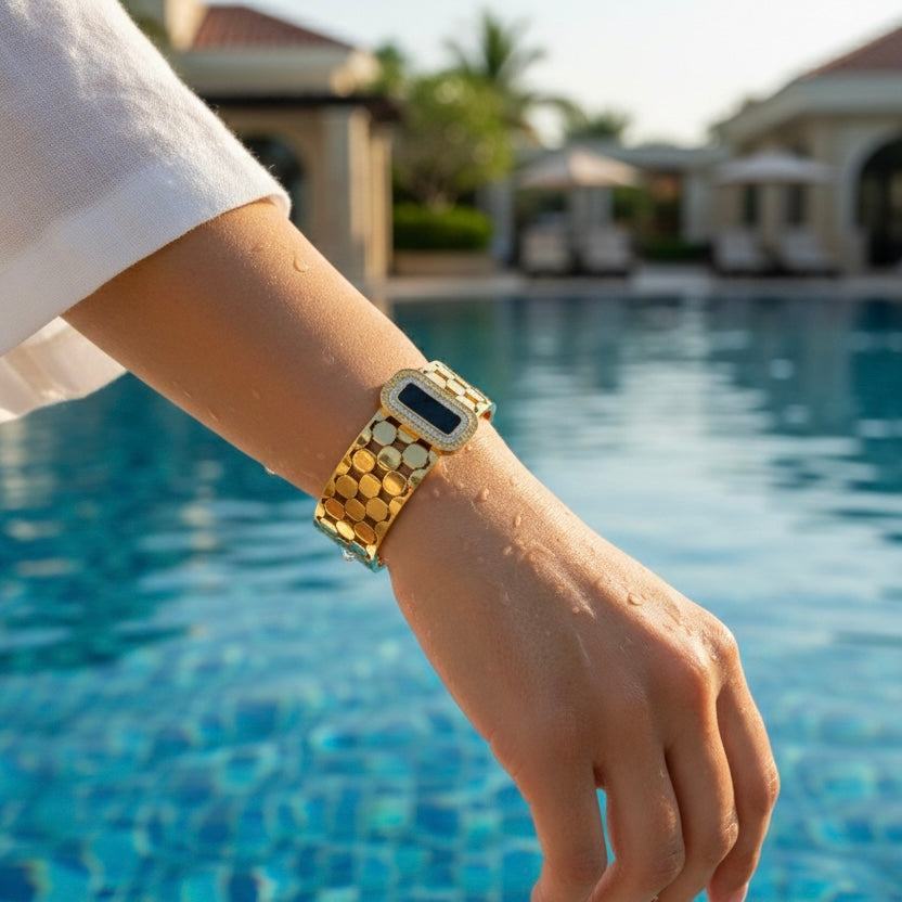 Gold bangle on a wrist with a pool and outdoor setting in the background