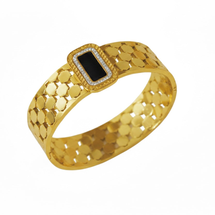 Gold bracelet with a black gemstone on a white background